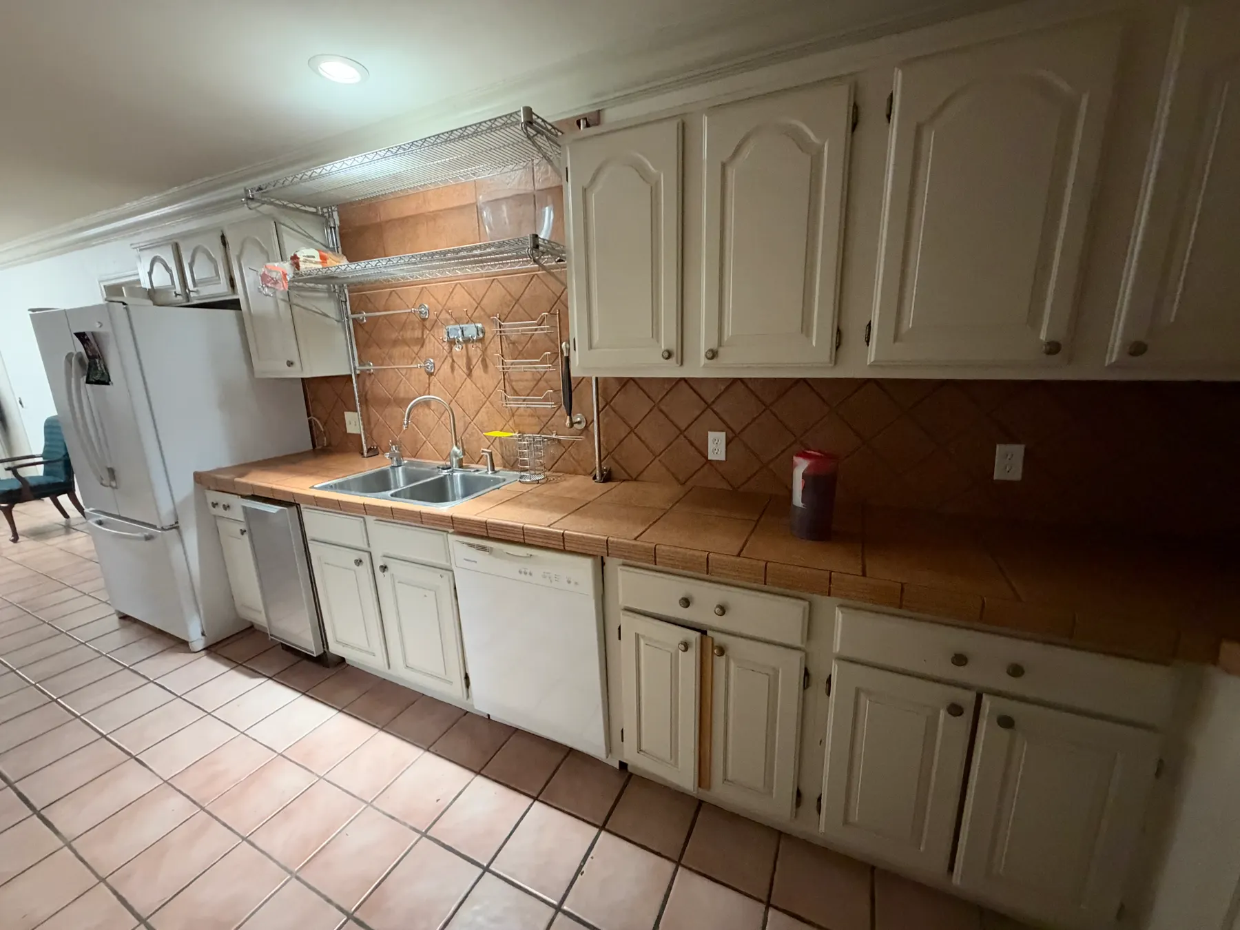 Shared kitchen with white cabinets and tile floor